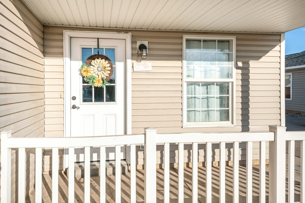 porch of a house with beige vinyl siding and railing