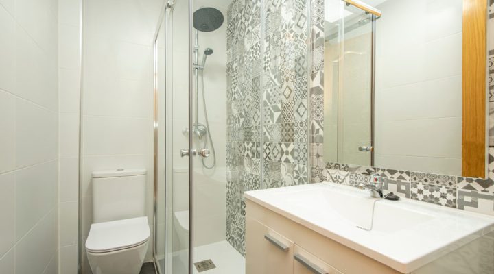 bathroom with smooth tiled walls, frameless square mirrors, and white cabinets